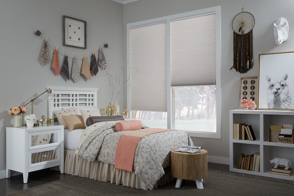 two large white Parasol® Cellular Shades behind a bed with white, tan, purple, and light pink Interior Masterpieces® Custom Pillows and Bedding
