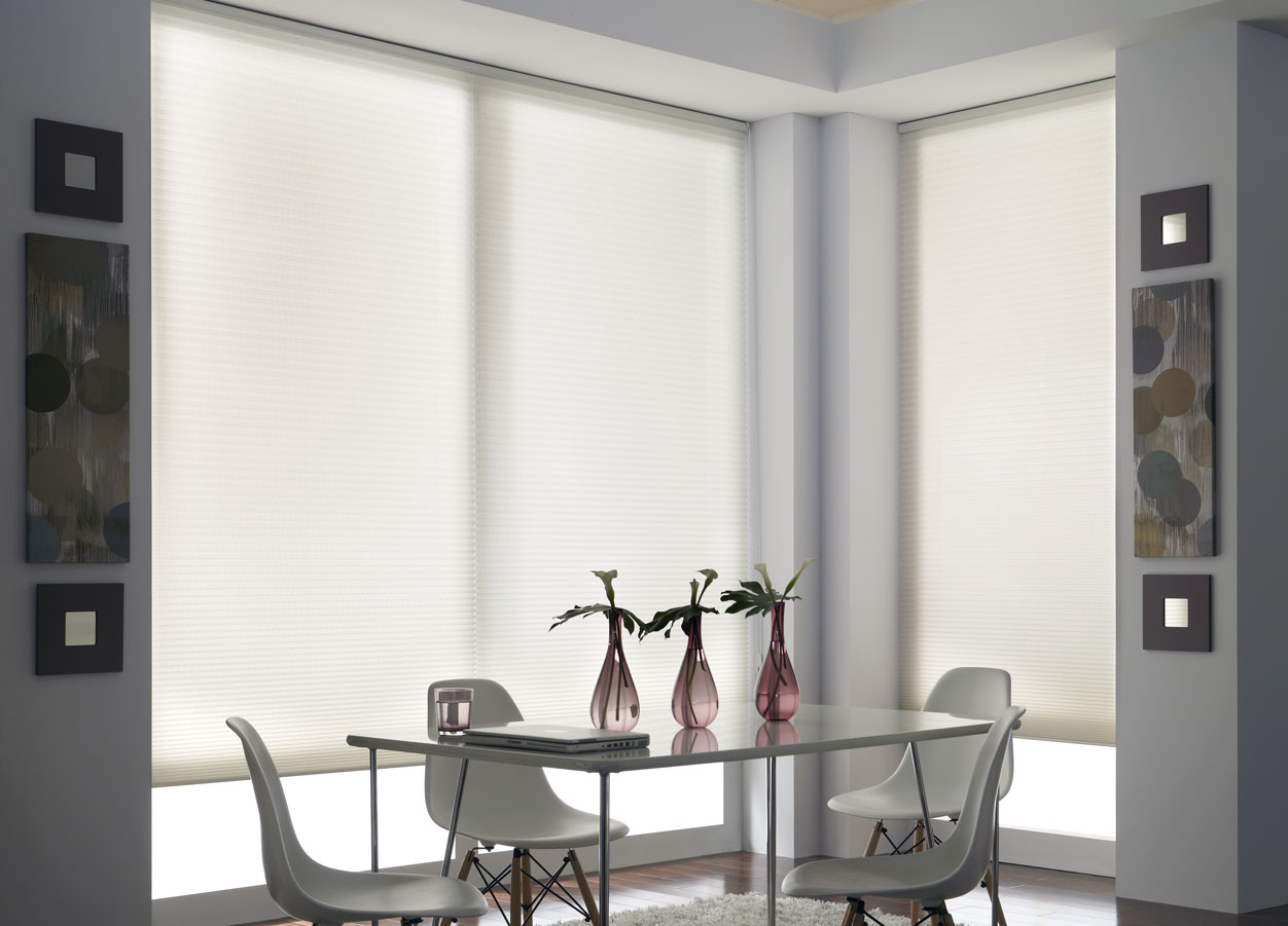 large white Parasol® Cellular Shades surrounding a glass table with gray chairs and pink flower vases