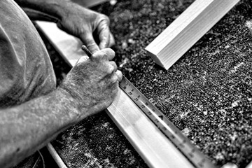 black and white photo of working hands measuring and marking