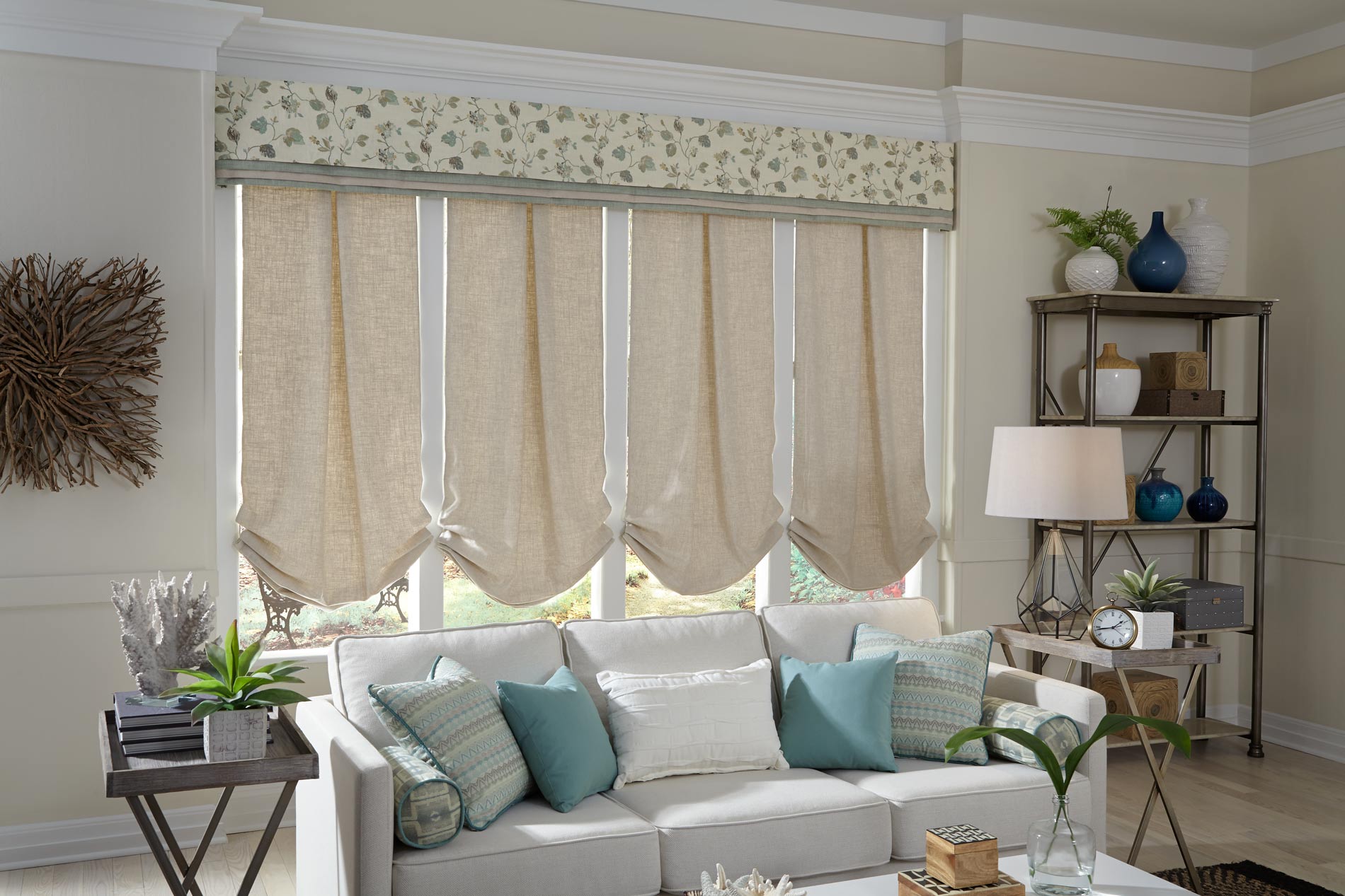 4 light tan Interior Masterpieces® fabric shades with a custom cornice spanning the width of all four and a light gray couch that has custom accent pillows